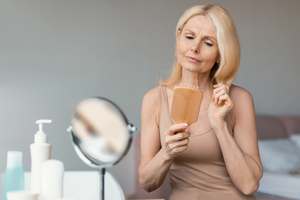 Reife Frau bürstet Haare kritisch