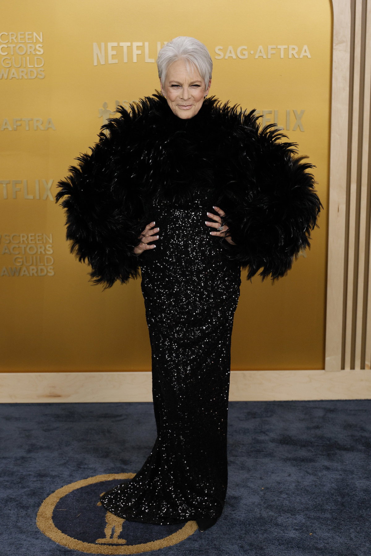 Jamie Lee Curtis mit einem Paillettenkleid und Feder-Bolero.