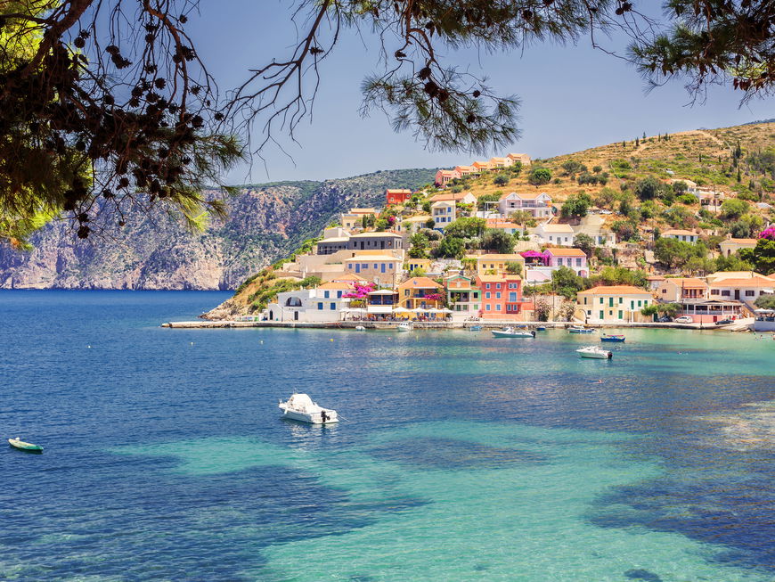 Die Küste von Kefalonia mit bunten Häusern und Booten auf dem Wasser.