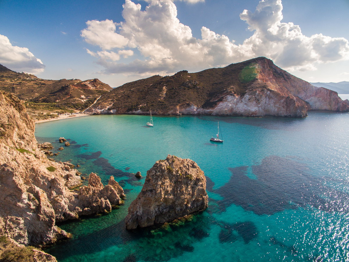 Das Meer an der Küste der Insel Milos mit zwei Segelbooten drauf.