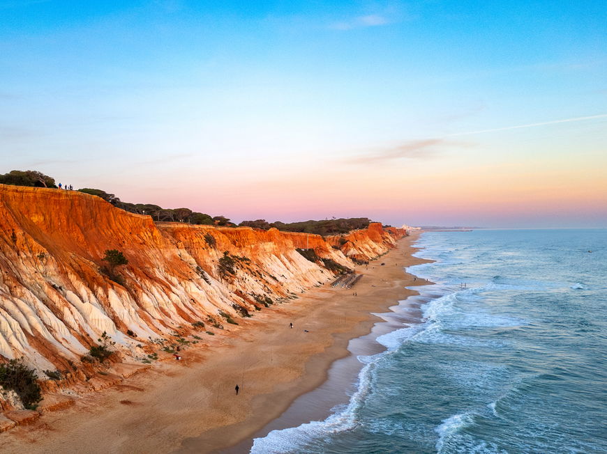 Rötliche Klippen und blaues Meer an der Praia da Falésia in Portugal.