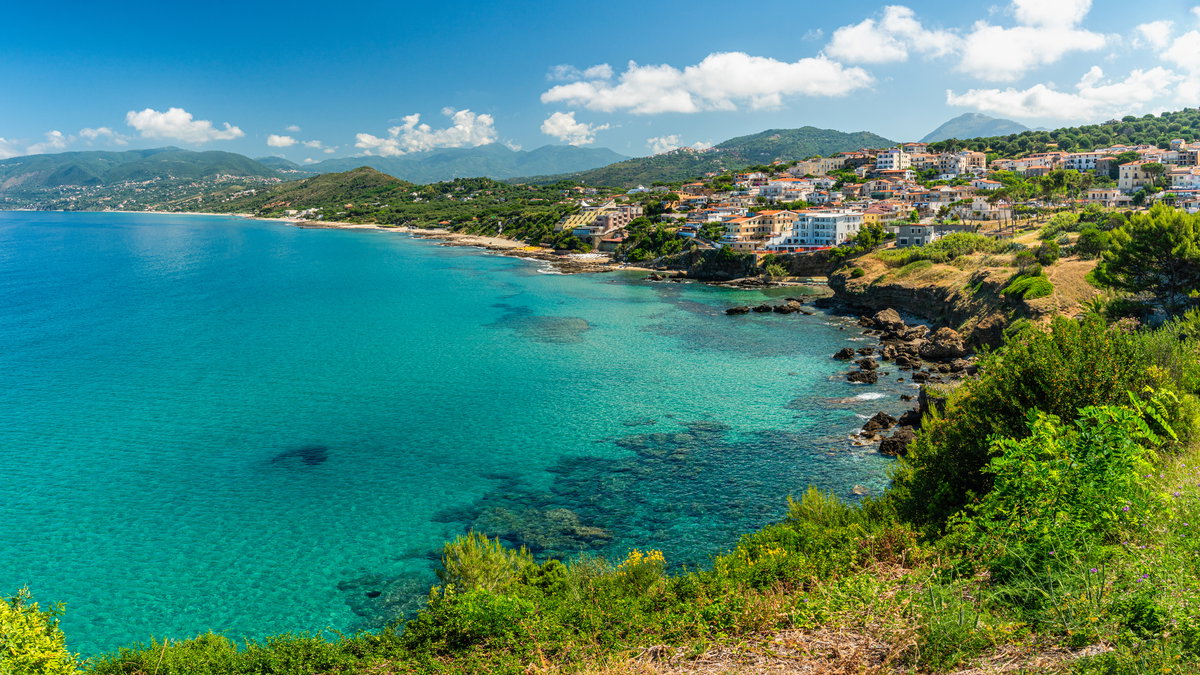 Die Küste von Cilento mit Häusern, viel Grün und türkisblauem Meer.