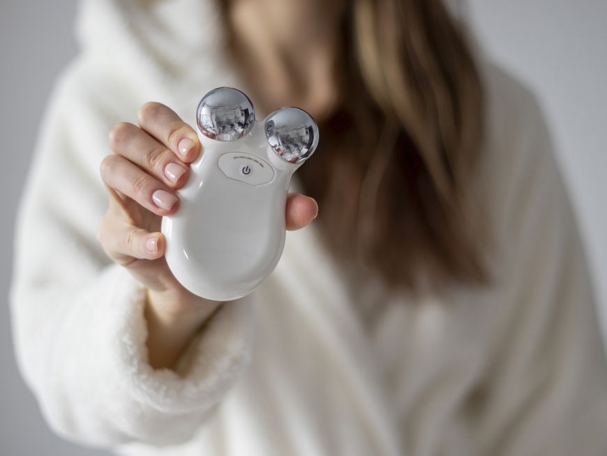 Frau hält ein Mikrostromgerät zur Massage des Gesichts in ihren Händen