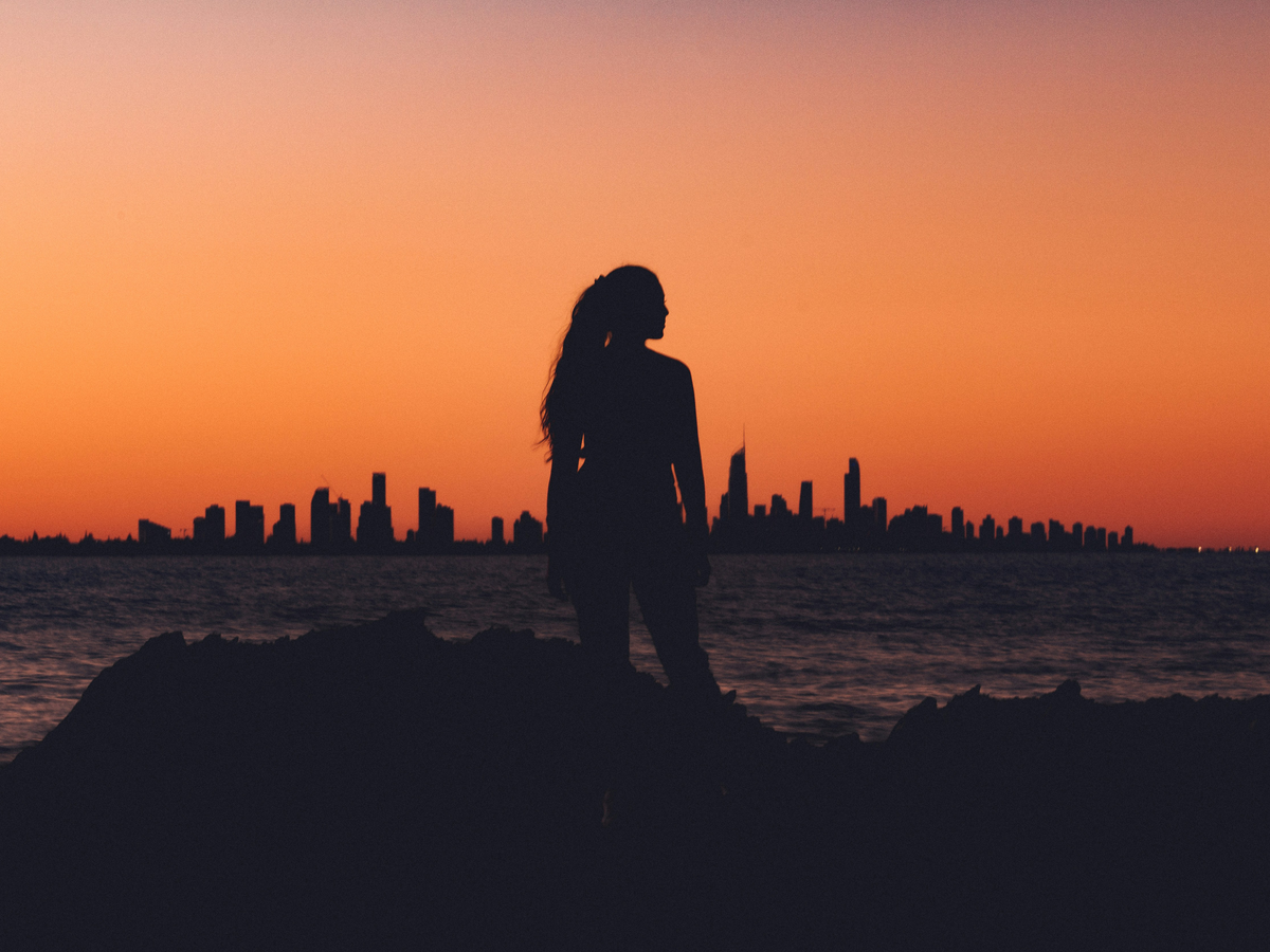 Frau steht vor Abendhimmel