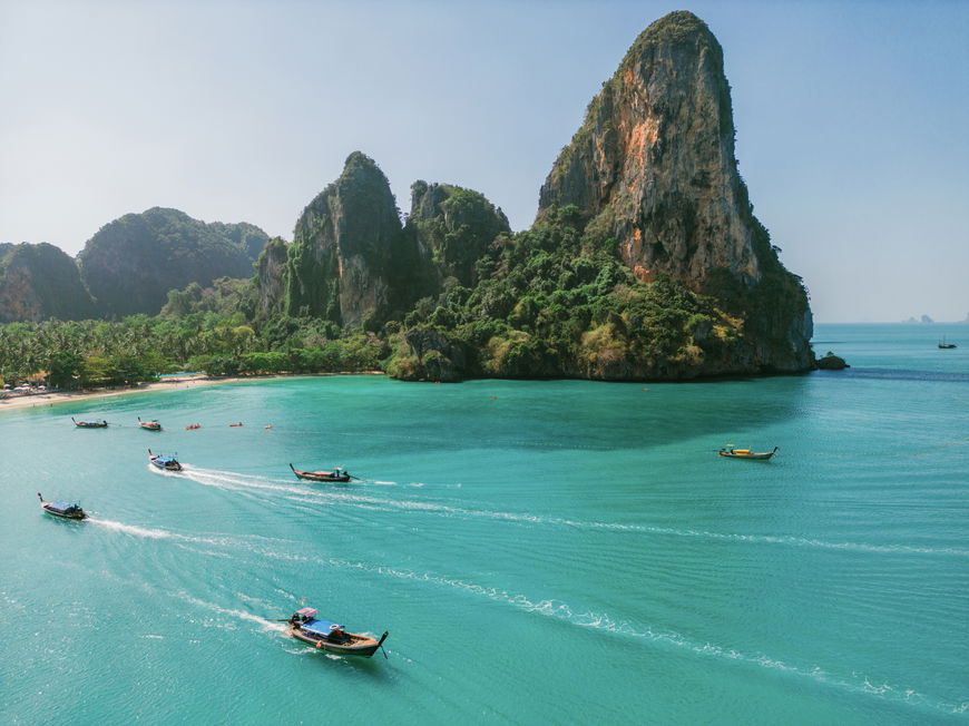 Die Küste von Krabi mit grünen Felsen und türkisblauem Meer und Booten.