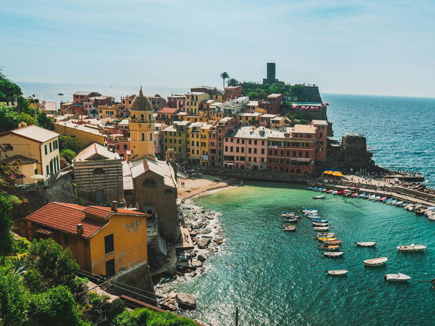 Die Küste von Vernazza in der Toskana mit bunten Häusern und Booten im Wasser.