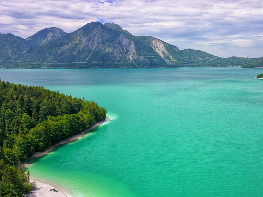 Ein riesiger, türkisfarbener See mit Gebirge im Hintergrund.