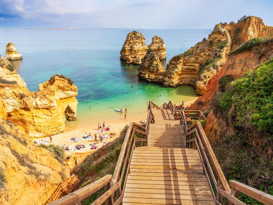 Ein Blick auf eine Holztreppe, die zum Camilo Beach herunter führt mit Menschen am Strand.