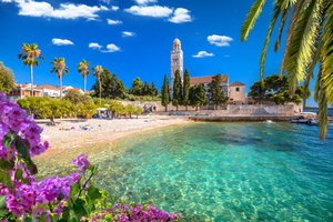 Strand mit ein paar Handtüchern, Palmen und einer Kirche im Hintergrund