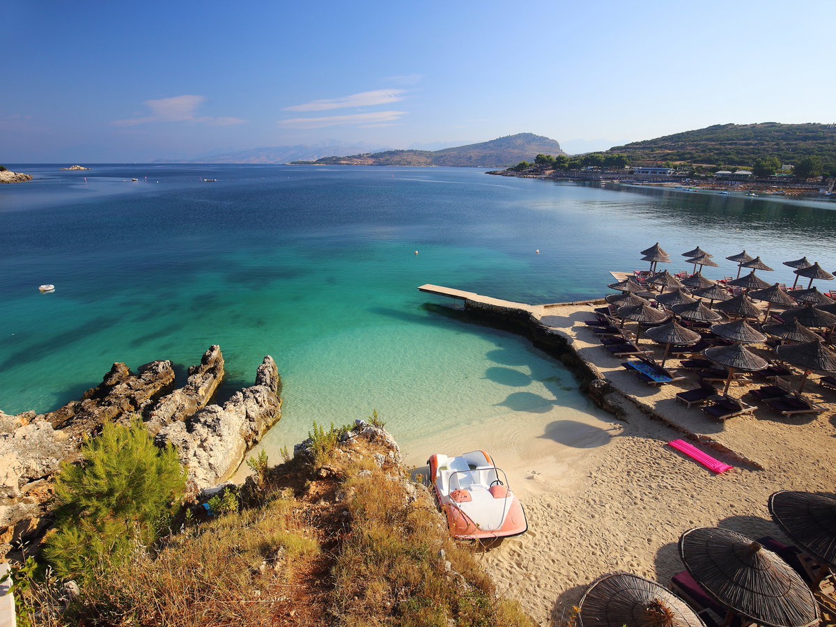 Ein Blick auf den Strand und das Meer von Ksamil mit Sonnenschirmen und Liegen.
