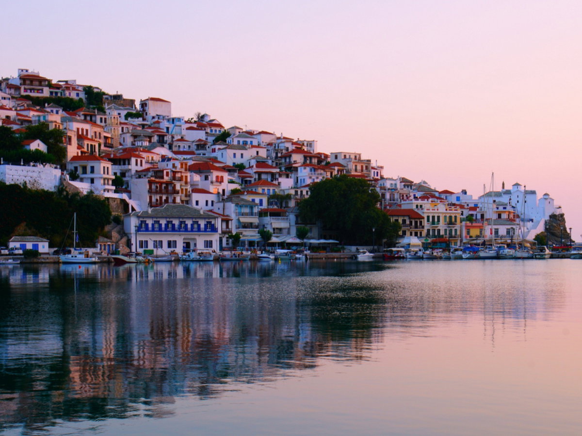 Ein Blick auf einen Hang mit Häusern an der Küste von Skopelos bei Sonnenuntergang