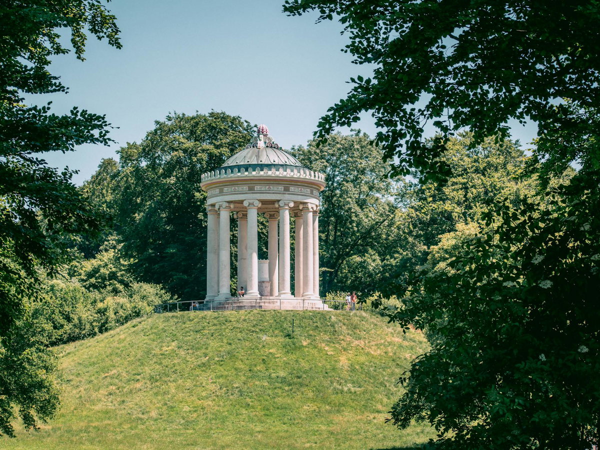 Ein Blick auf einen Pavillon aus Stein auf einem Hügel in einem großen Garten.