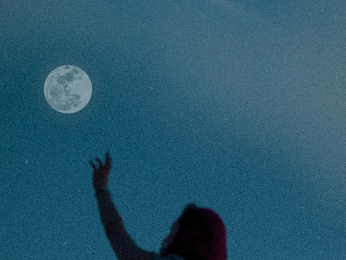 Frau streckt Arm zum Mond