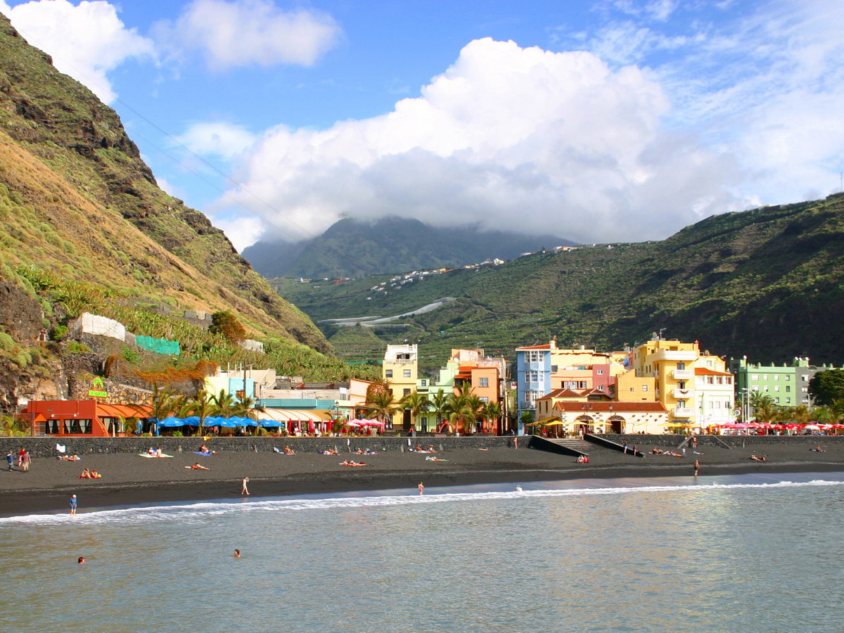 Bunte Häuser an der Küste von La Palma an einem Strand mit dunklem Sand.