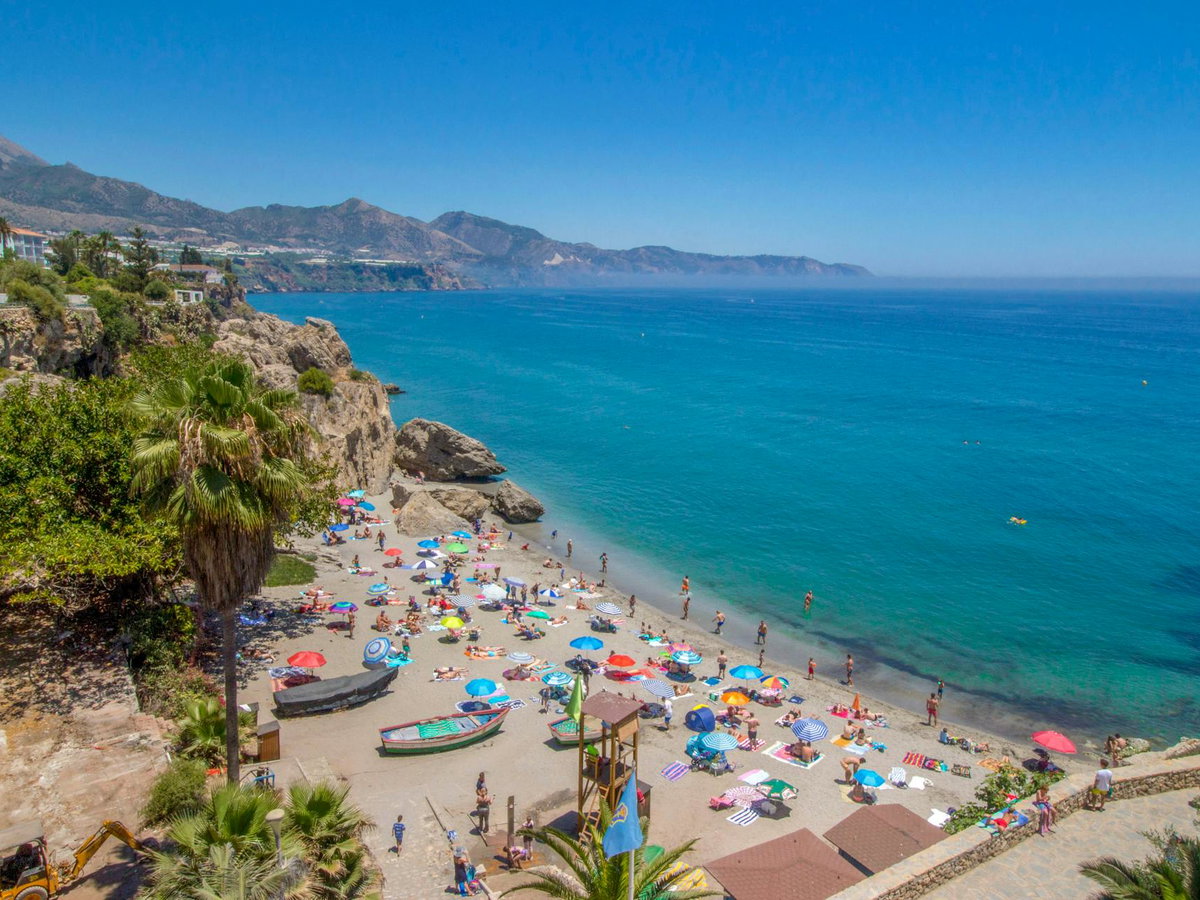 Ein Strand in Malaga mit vielen Menschen und Sonnenschirmen.