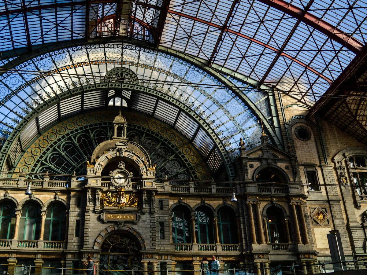 Der Bahnhof von Antwerpen mit einer großen Uhr, vielen Details und einem Dach aus Glas.