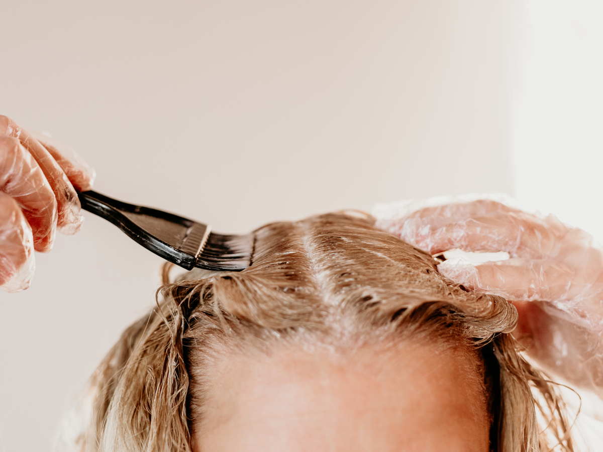 Frau färbt Haare blond.
