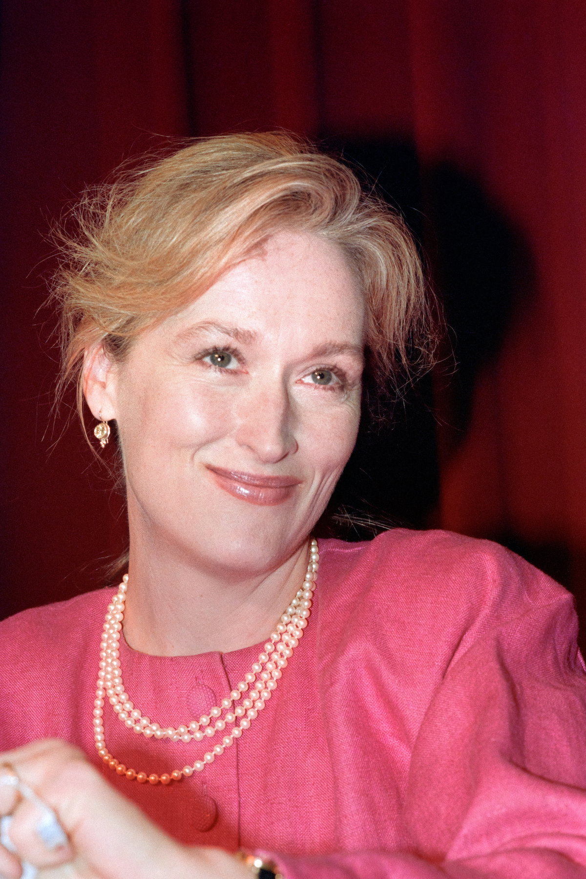 Meryl Streep mit drei Perlenketten und einem pinken Oberteil.