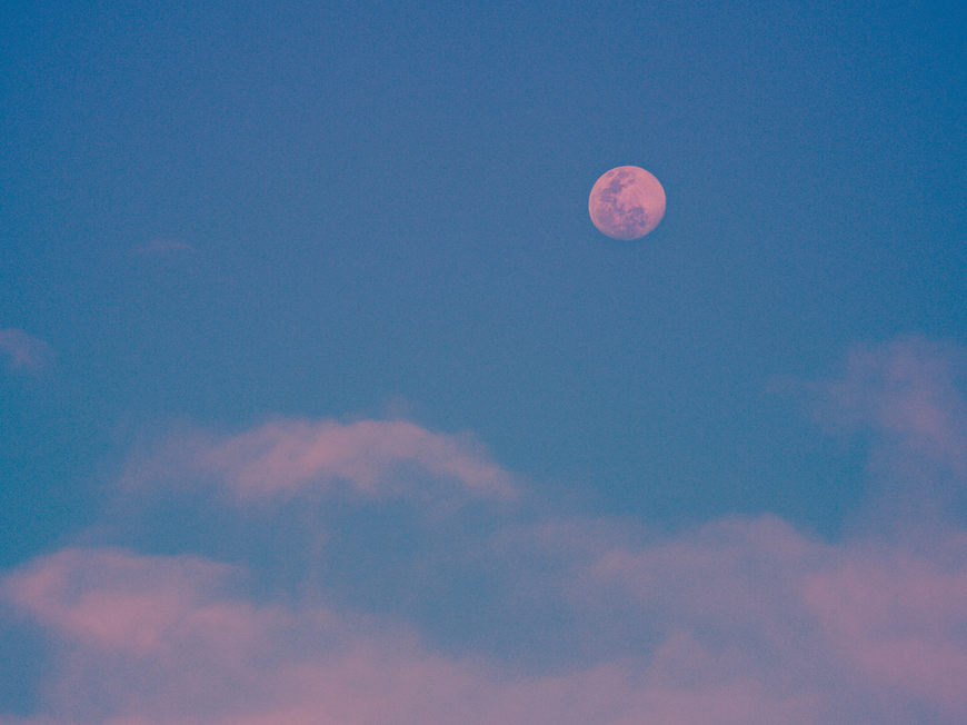 Blauer Himmel mit rosa Mond und rosa Wolken
