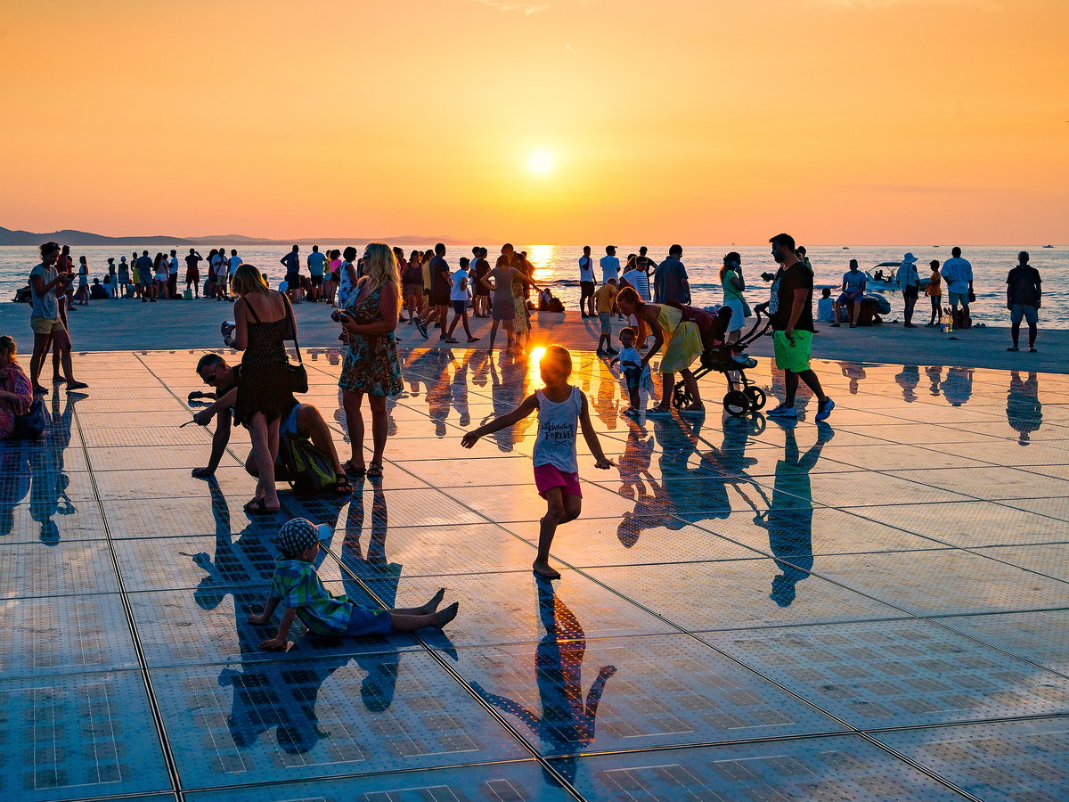 Ein Sonnenuntergang mit Blick aufs Meer mit vielen Menschen davor.
