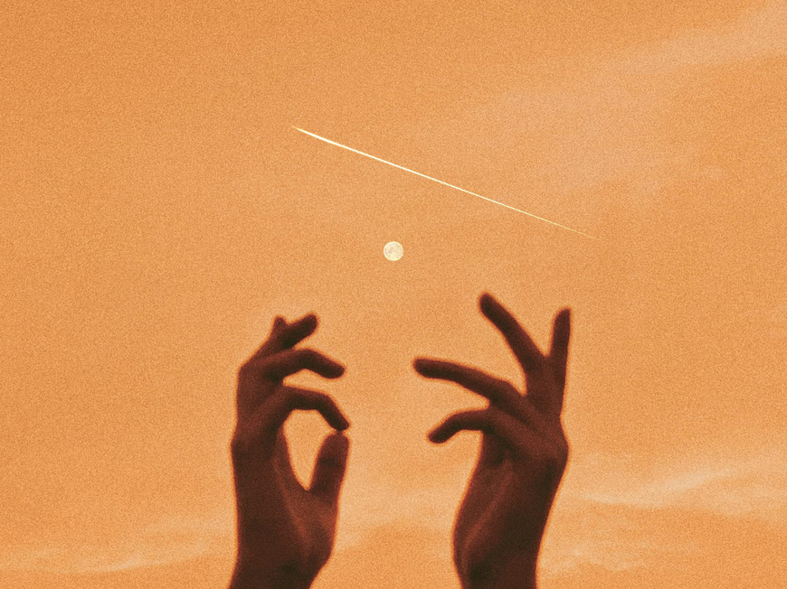 Hände vor goldenem Mondhimmel