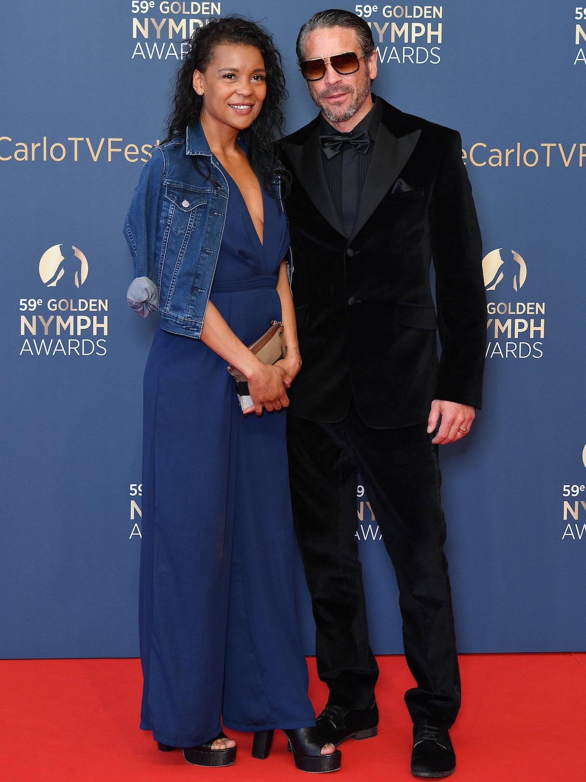 Ola Rapace in einem schwarzen Samt-Anzug mit Begleitung einer Frau in einem dunkelblauen Kleid.
