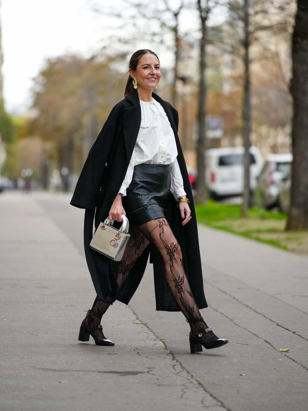Frau mit weißer Bluse, Blazer, Shorts und Riemchen-Pumps mit Blockabsatz.