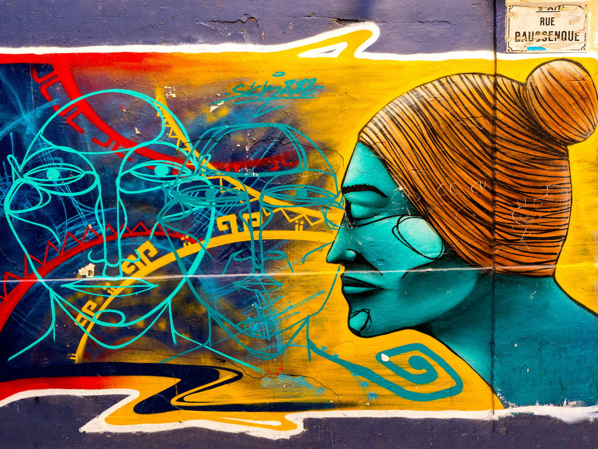 Bunte Street Art an einer Wand, auf der ein türkisfarbener Kopf von der Seite mit weiteren Umrissen und Linien zu sehen ist.