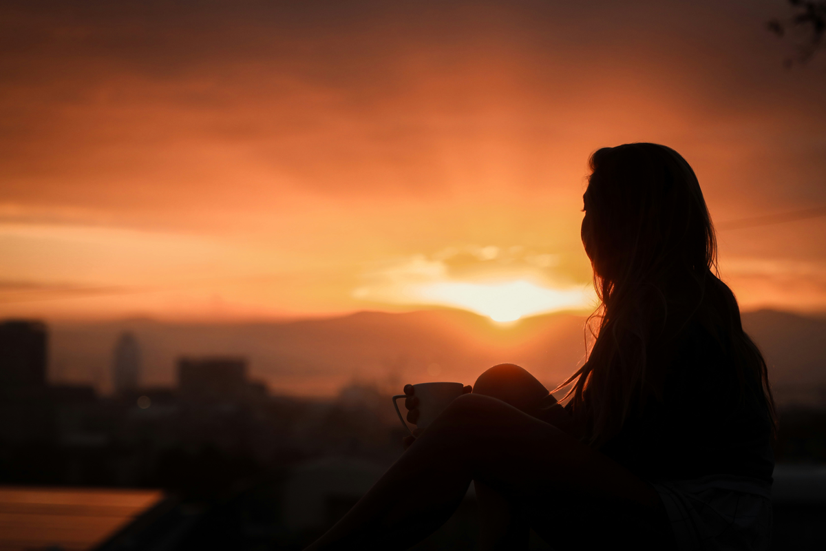 Frau schaut in den Sonnenaufgang