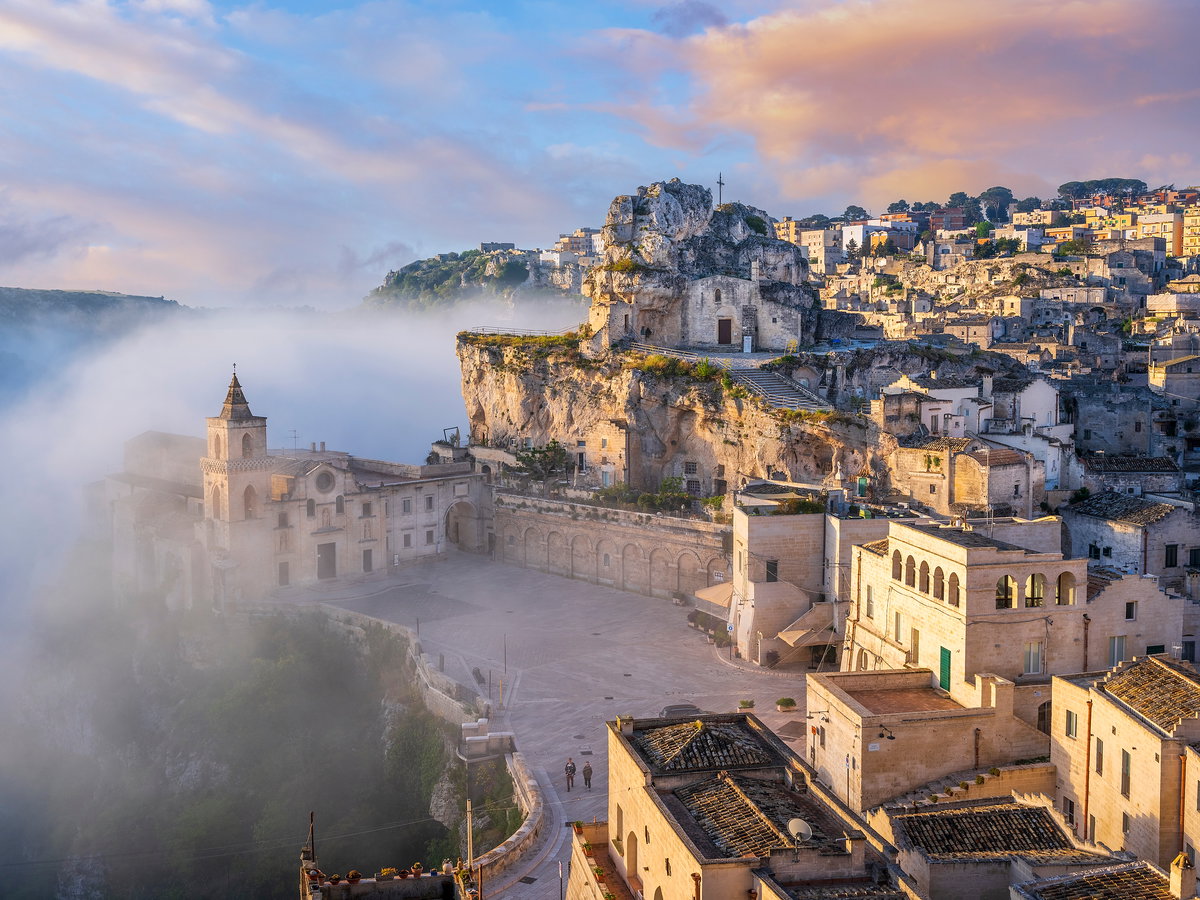 Ein Blick auf Matera mit vielen beigefarbenen Häusern und Nebel drum herum.