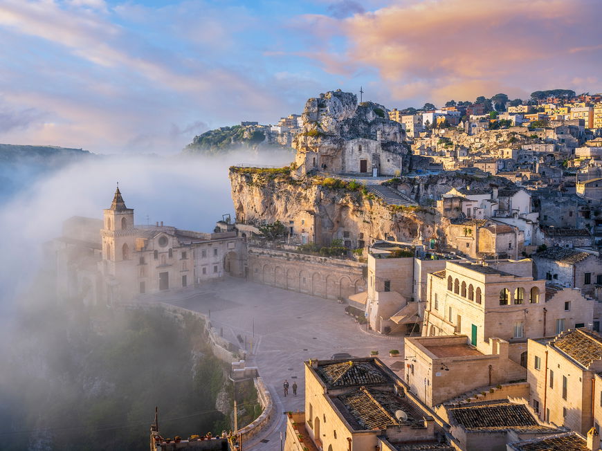 Ein Blick auf Matera mit vielen beigefarbenen Häusern und Nebel drum herum.