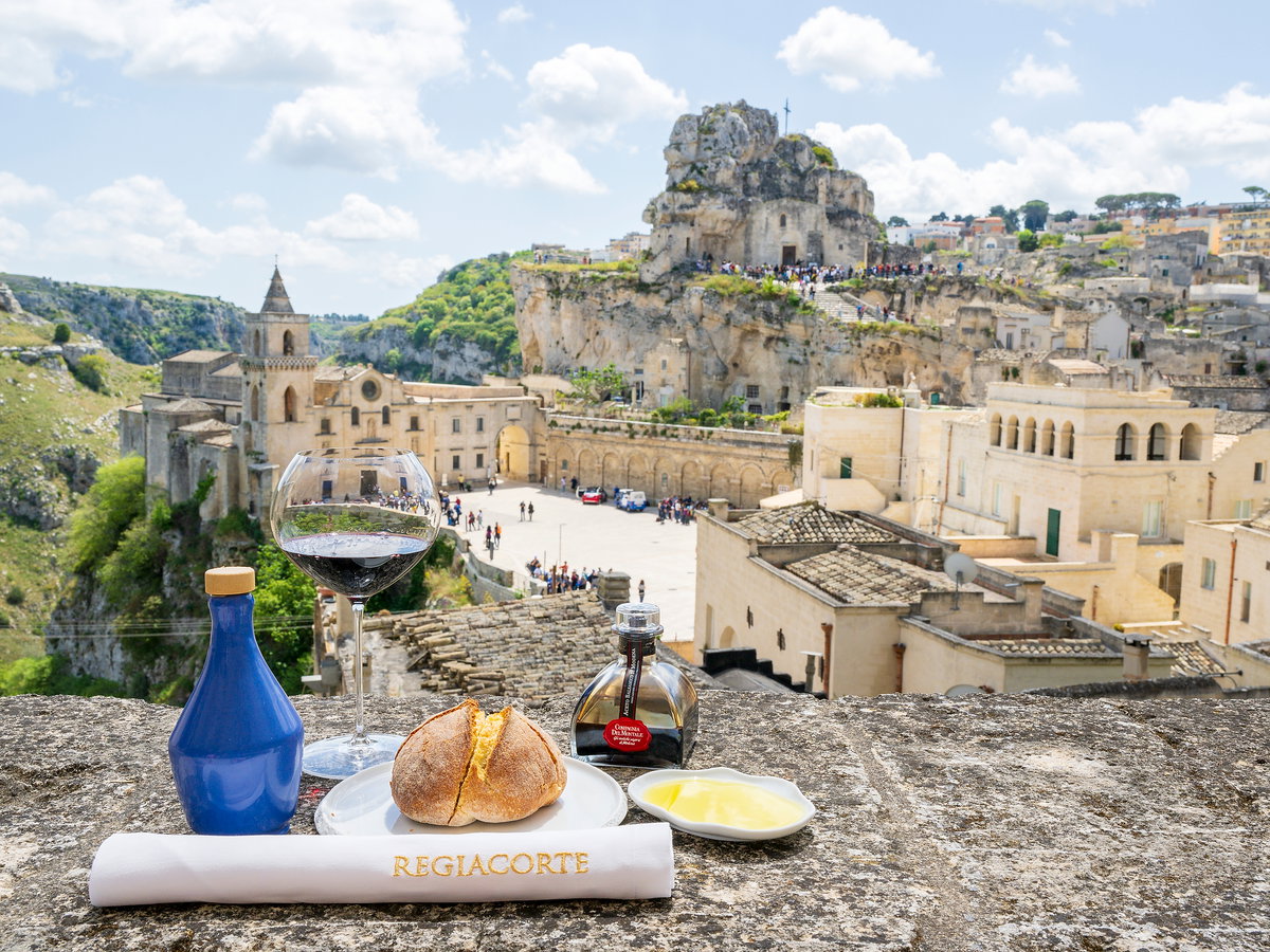 Ein Brötchen und ein Weinglas auf einer Mauer mit einer Burg im Hintergrund.