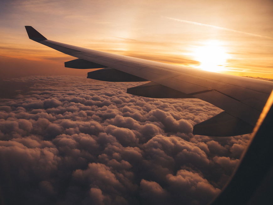 Ein Flugzeug fliegt Richtung Sonnenaufgang