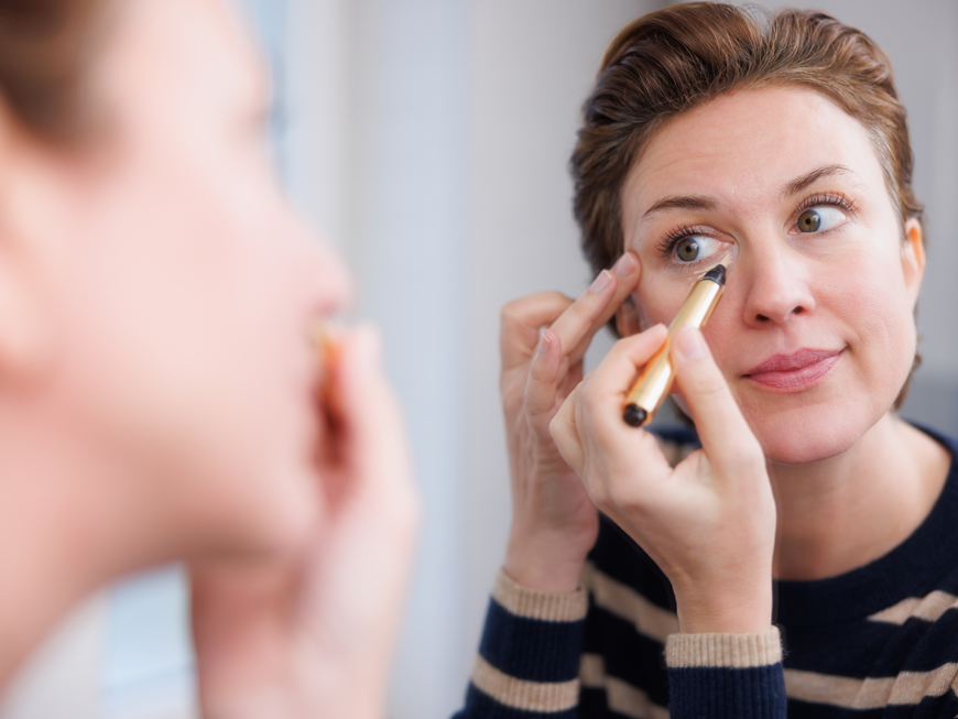 Frau trägt Concealer auf
