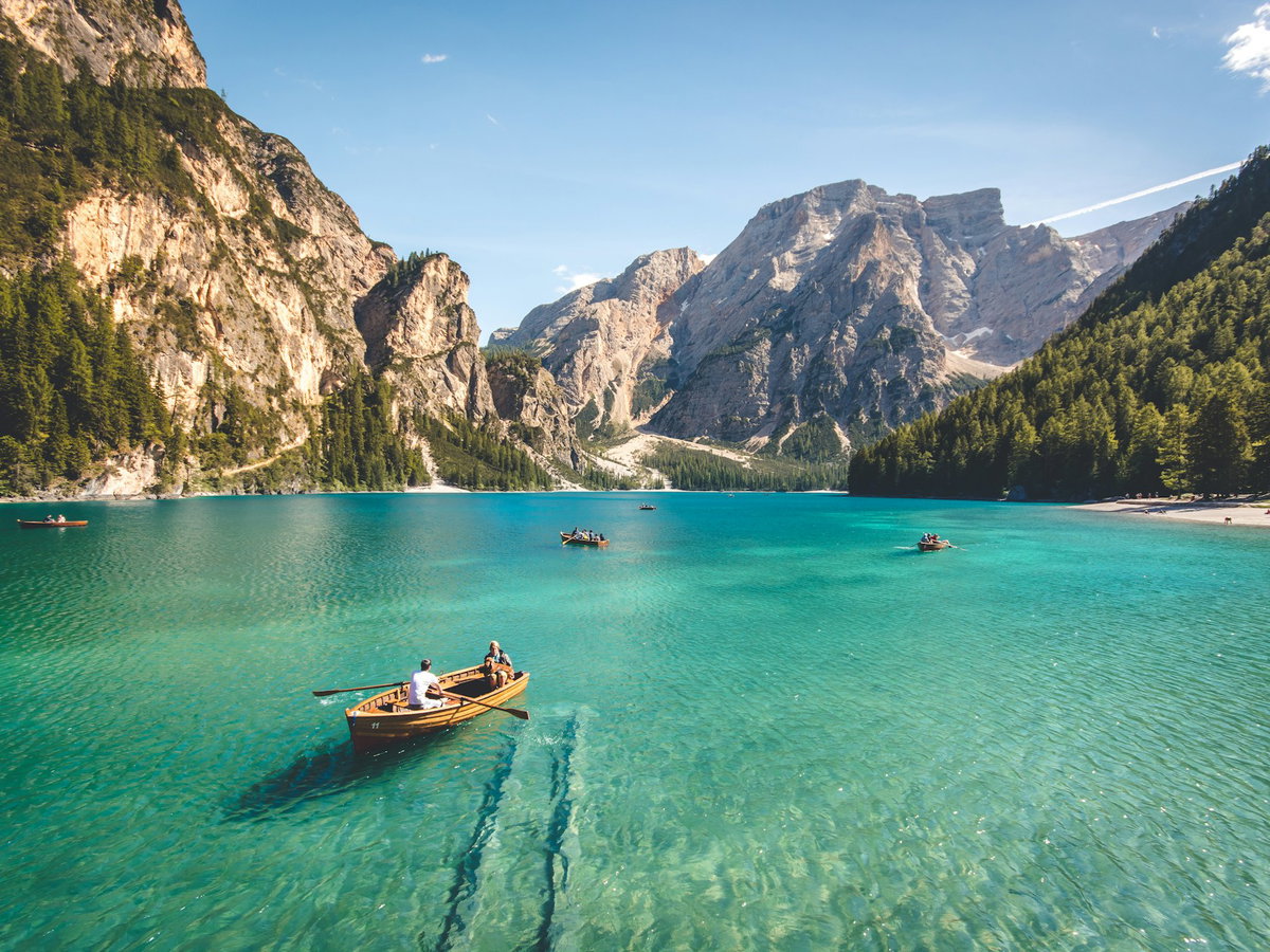 Ein großer See mit Gebirge im Hintergrund und ein paar Booten auf dem Wasser.