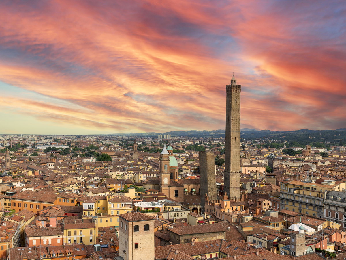 Ein Blick über die Dächer von Bologna bei einem rötlichen Himmel.