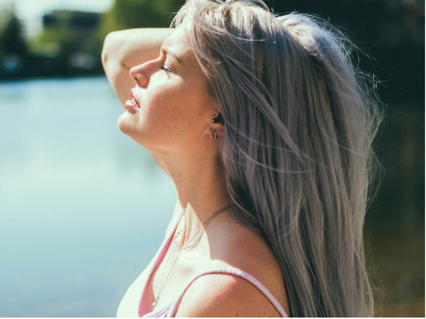 Eine Frau hält ihr Gesicht in die Sonne