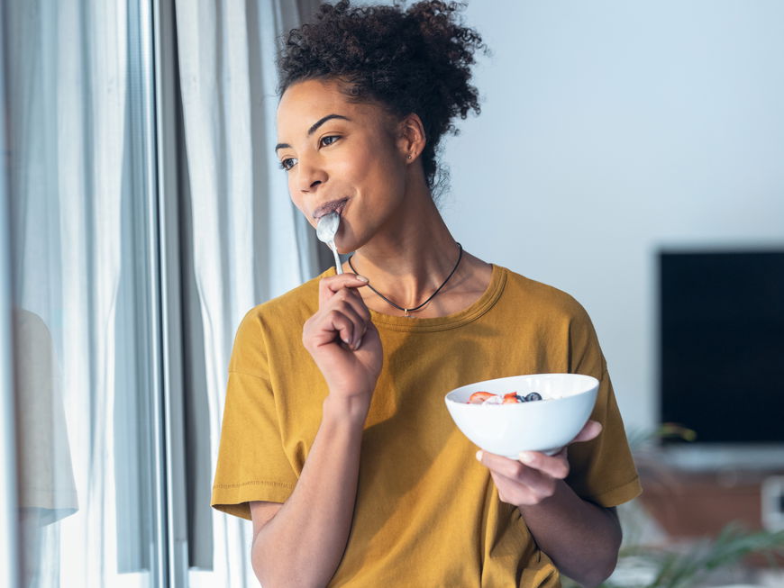 Eine Frau isst einen Joghurt mit Früchten