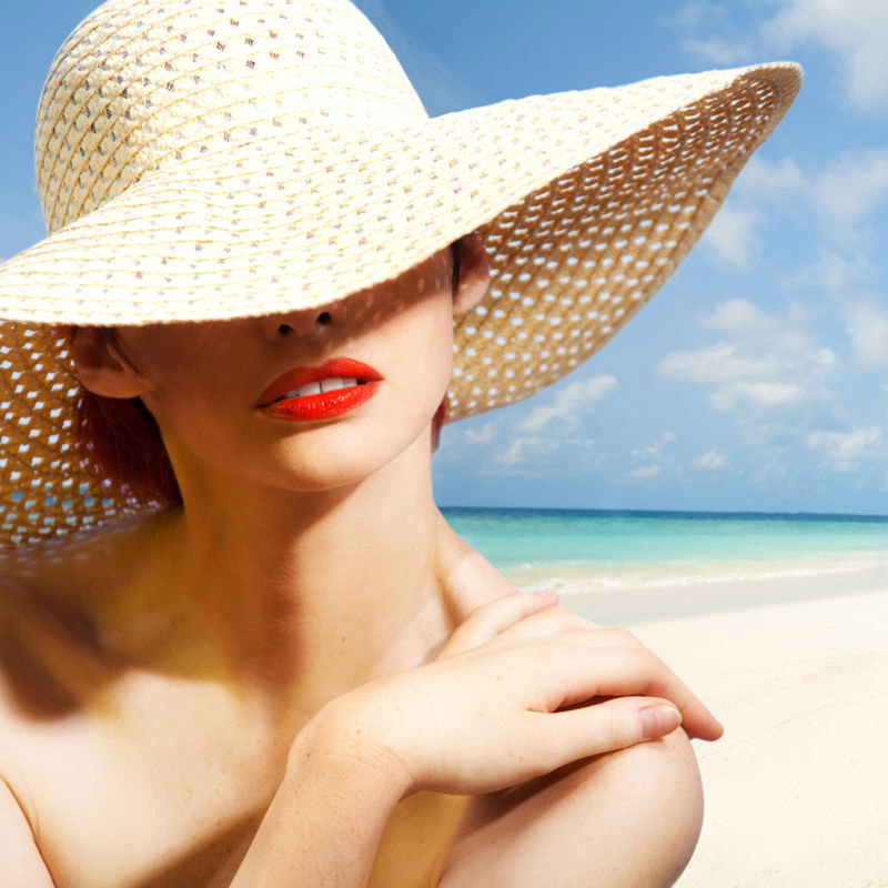 Frau mit Sonnenhut am Strand