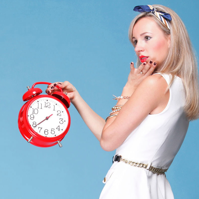 Junge Frau hält rote Uhr