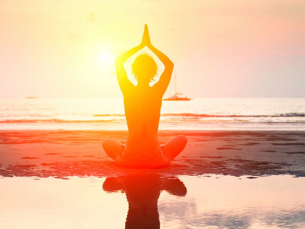 Frau macht Yoga am Strand.