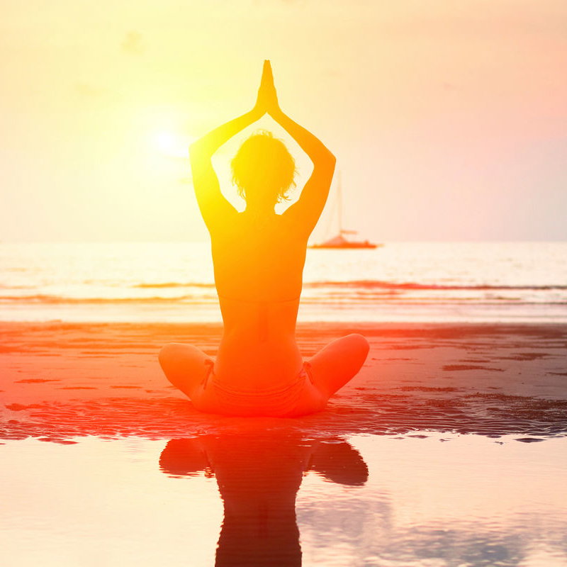 Frau macht Yoga am Strand.