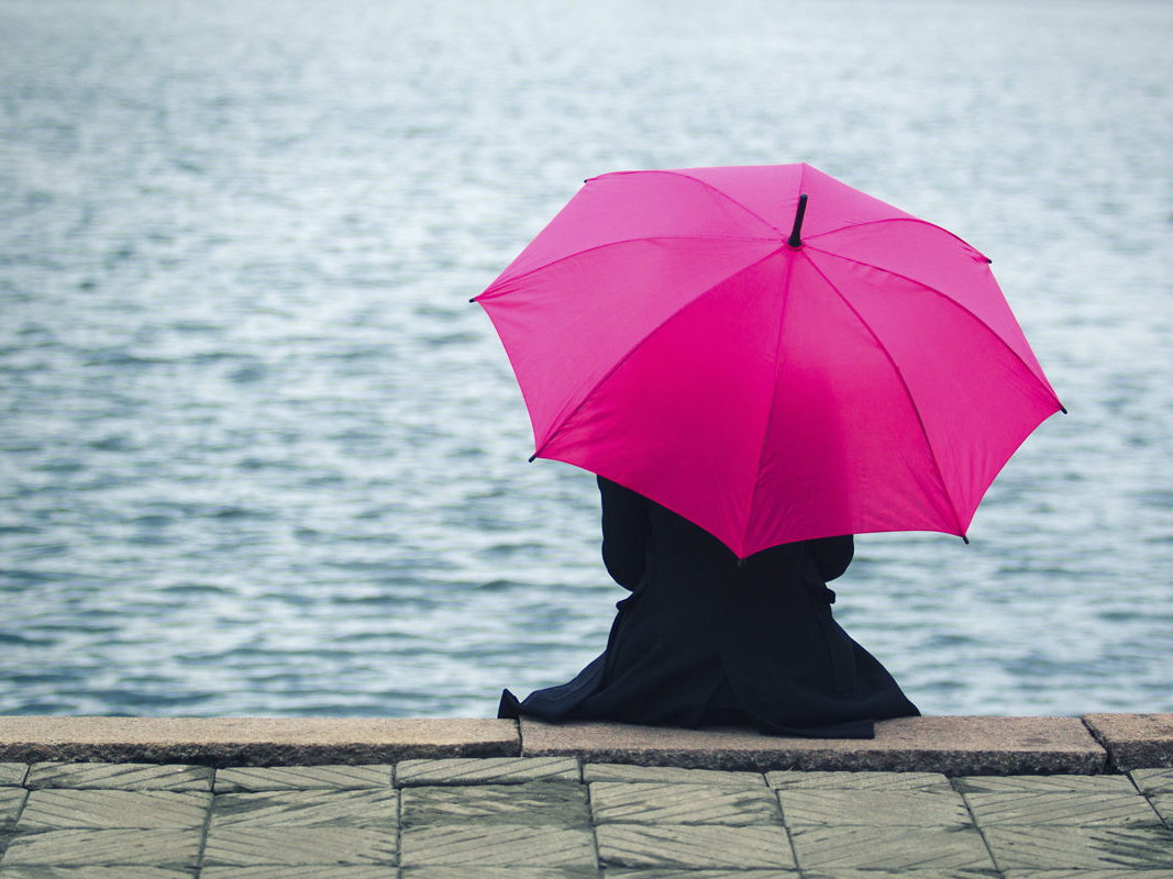 Frau mit Regenschirm am See
