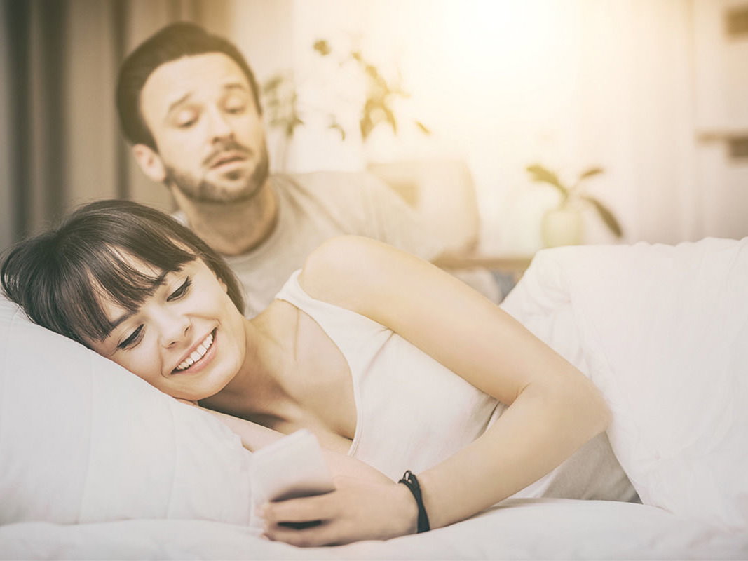 Eine Frau schaut auf ihr Handy - geht sie online fremd?