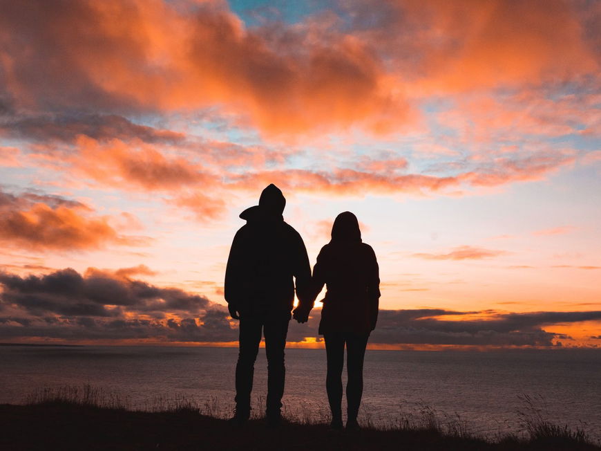 Frau und Mann von hinten schauen sich den Sonnenuntergang an.