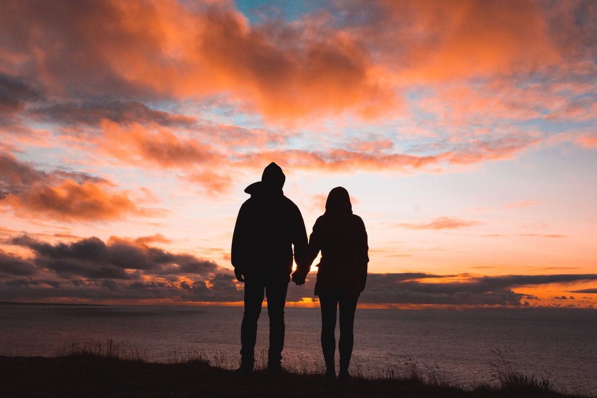 Frau und Mann von hinten schauen sich den Sonnenuntergang an.